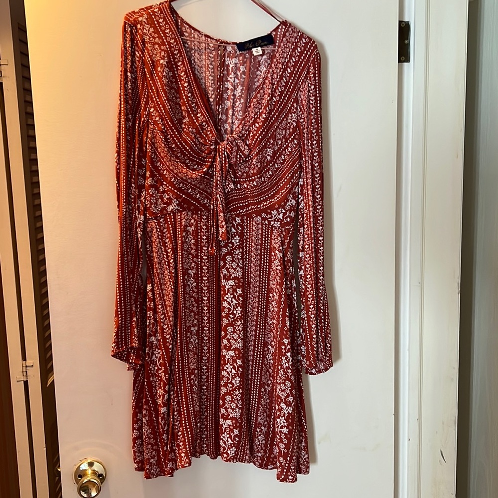 Orange/rust color long sleeve dress with white flowers. Bow in the front chest